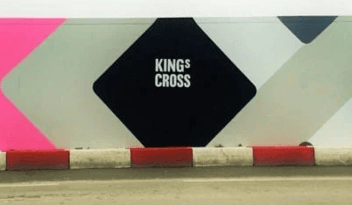 An abstractive wall sign on the street that says 'King's Cross' 