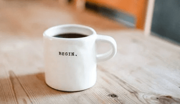 A mug full of coffee that says 'Begins'