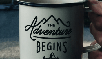 A mug that says 'The Adventure begins'
