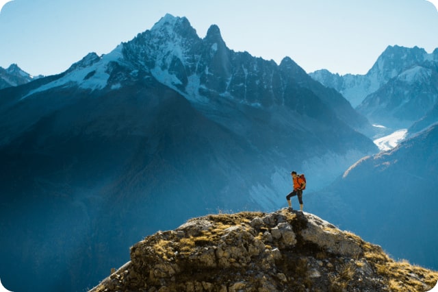 A hiker on top of a rocky summit in the mountains of the Alps-min-min