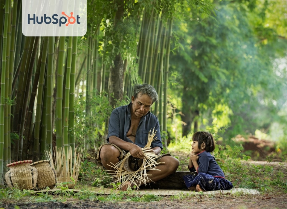 A man is crafting baskets made from bamboo materials in the forest, while a young girl watches closely.